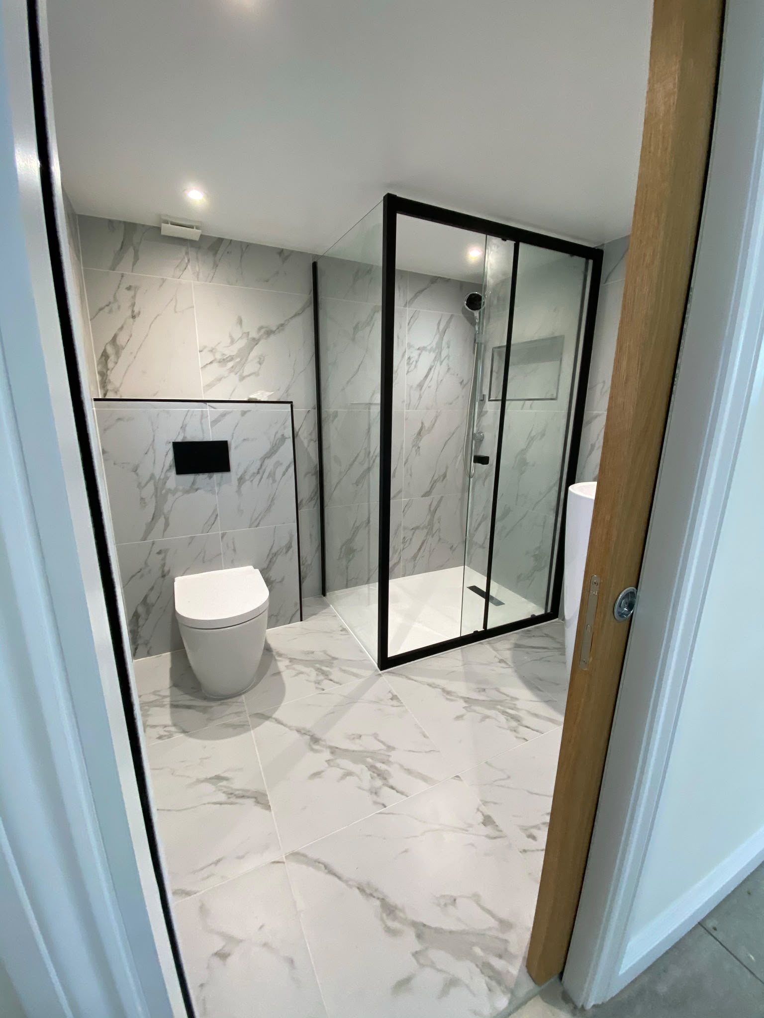 Completed marble-effect bathroom with black-framed shower by Max Space